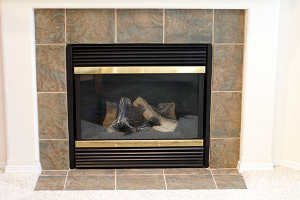 A gas fireplace in a home with surrounding tile.