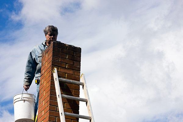 A man standing at his chimney looking for common fireplace problems.