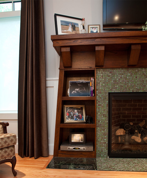 Cozy fireplace design with a green tile surround and wooden shelving mantel.