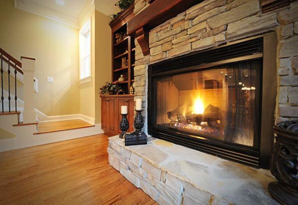 A bright fire burning in a gas insert fireplace with a stone veneer
