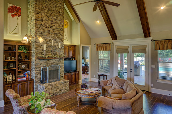 Living room with stone fireplace with three-fold fireplace screen and wood mantel.