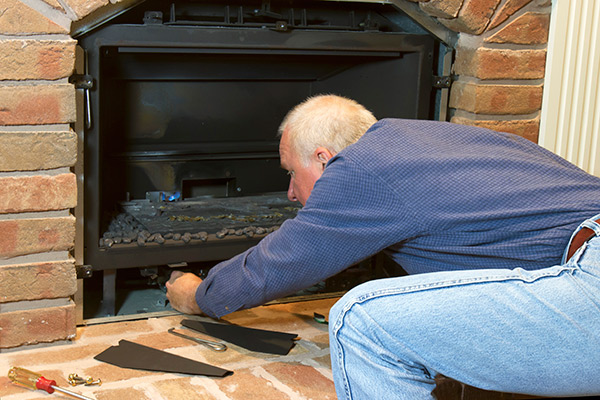 Man performing maintenance on a gas fireplace.