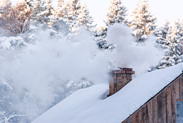  A smoking chimney covered in snow during the winter.