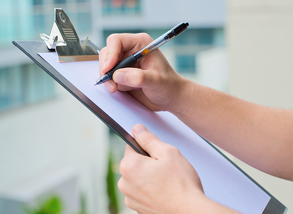 A person holding a clipboard to start a chimney inspection checklist