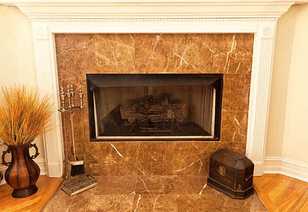 A gas insert fireplace surrounded by marble tile.