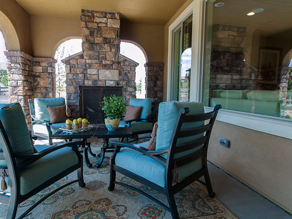 A large stone fireplace is the focal point of a covered outdoor stylish living area.