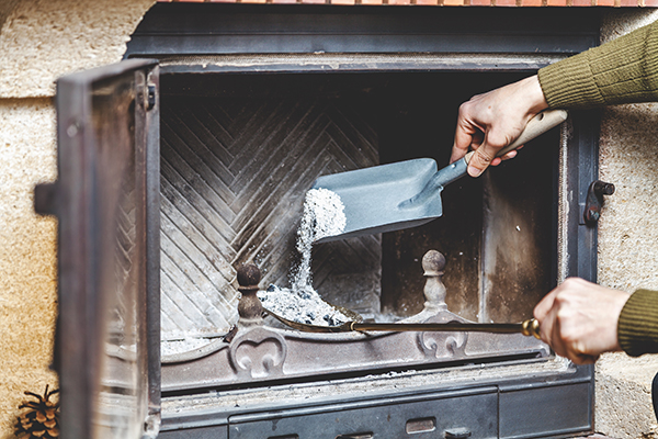 Ash is shoveled out of the firebox as part of good winter fireplace and chimney care.