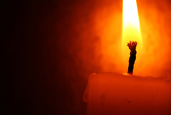 A lit candle producing soot stains in a dark room