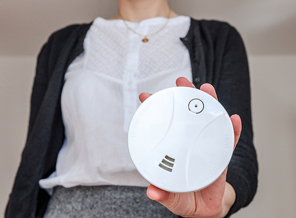 Woman holding a carbon monoxide detector, the best protection from carbon monoxide risks