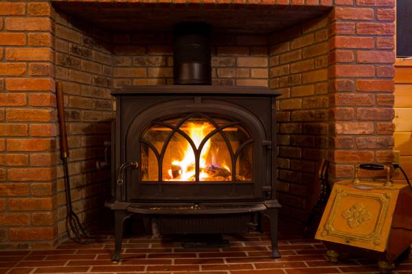 A fire burns brightly inside a wood stove. Heating efficiency for your whole home can be improved with wood stove heating.