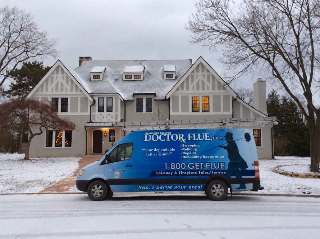 A Doctor Flue branded van outside a large Tudor-style home