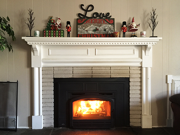 mantel decorated in a whimsical style with vibrant nutcracker and santa figurines, a present, a sign, and small trees
