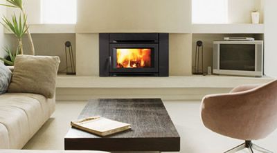 Black wood insert with a glowing fire set into a white fireplace wall